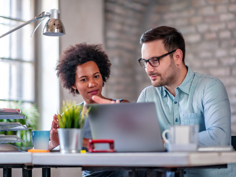 Photo of two coworkers working together on new project in office.